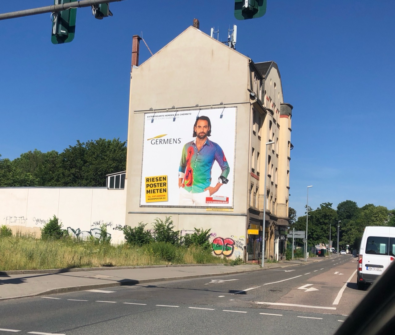 Mann mit farbenfrohem GERMENS-Hemd auf einem Fassadenplakat