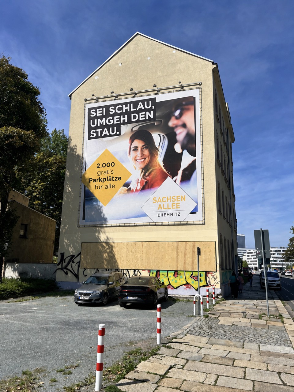 Sachsen-Allee-Plakat mit zwei Personen im Auto und dem Schriftzug Sei schlau, umgeh den Stau